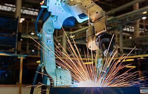 Robot is welding metal part in car factory