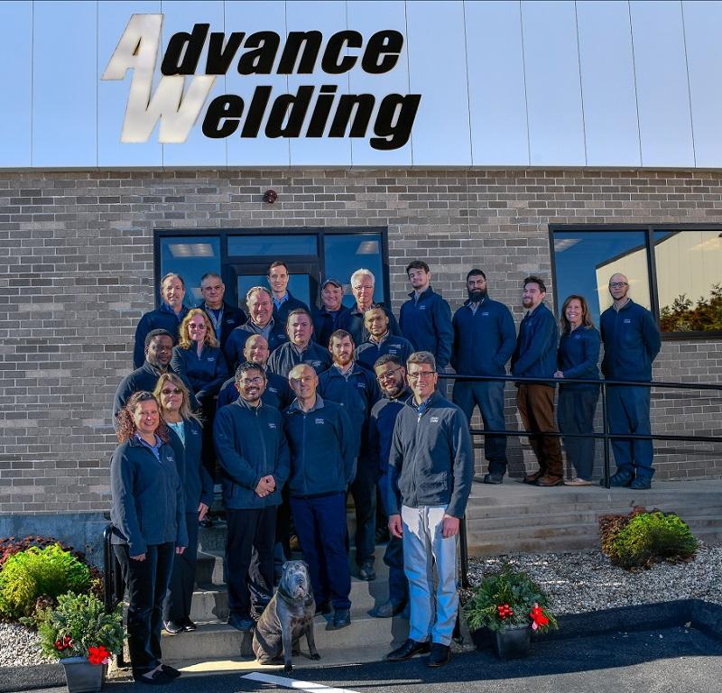 Advance Welding employees pose in front of the company building.