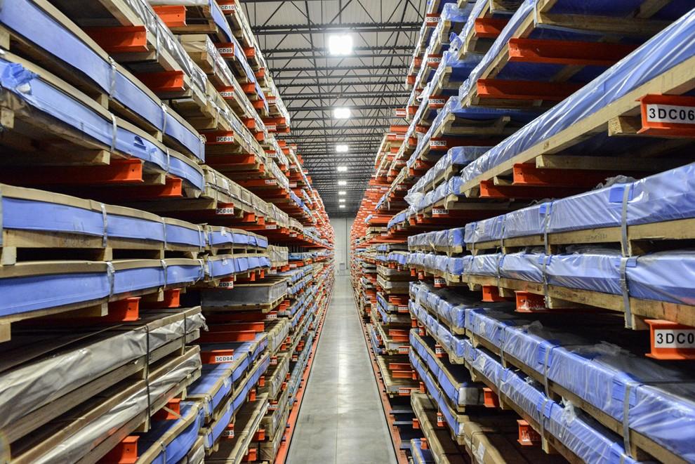 A few down a warehouse aisle with shelves stacked with material on both sides.