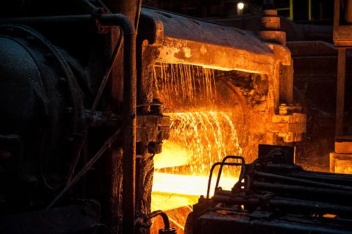 A sheet of hot metal emerges from the rolling mill.