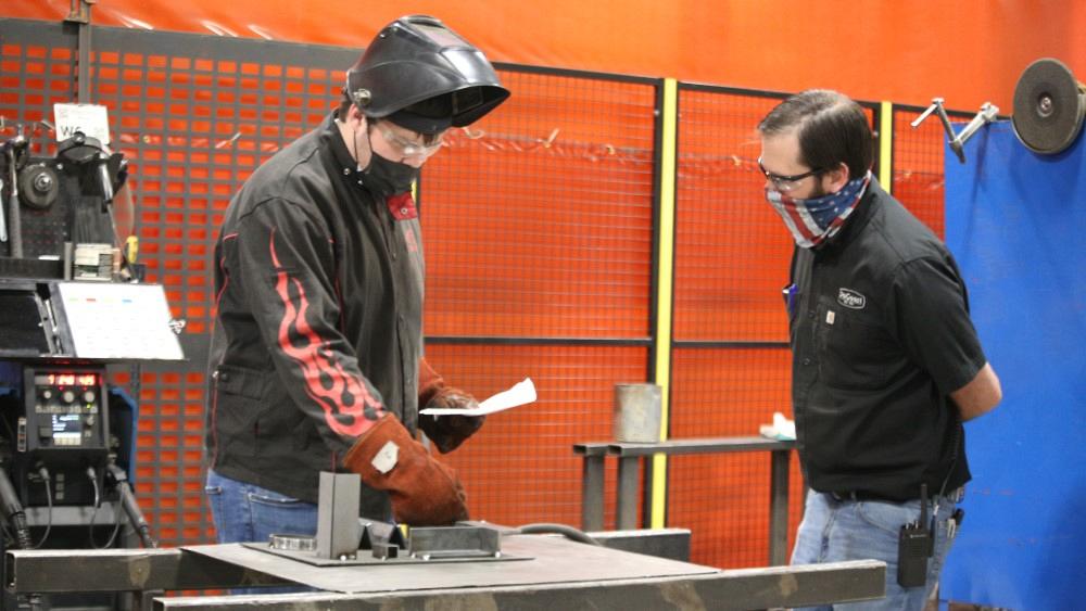 A judge consults with a student welder.