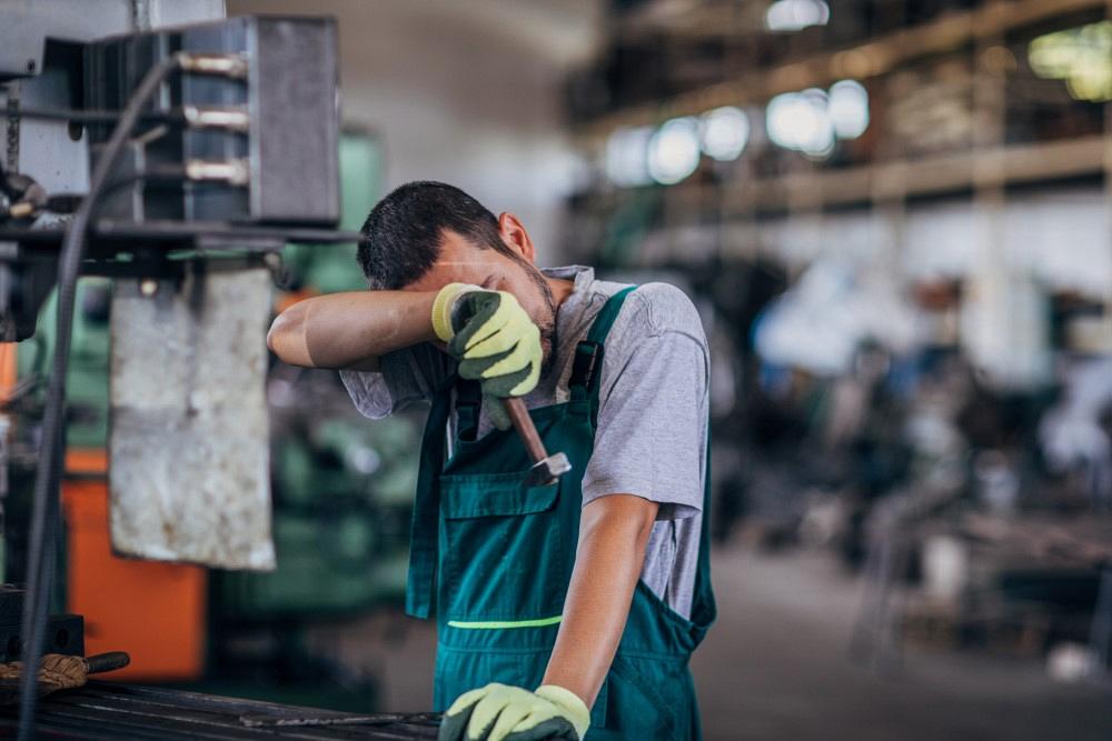 Tired guy working on a machine in factory workshop