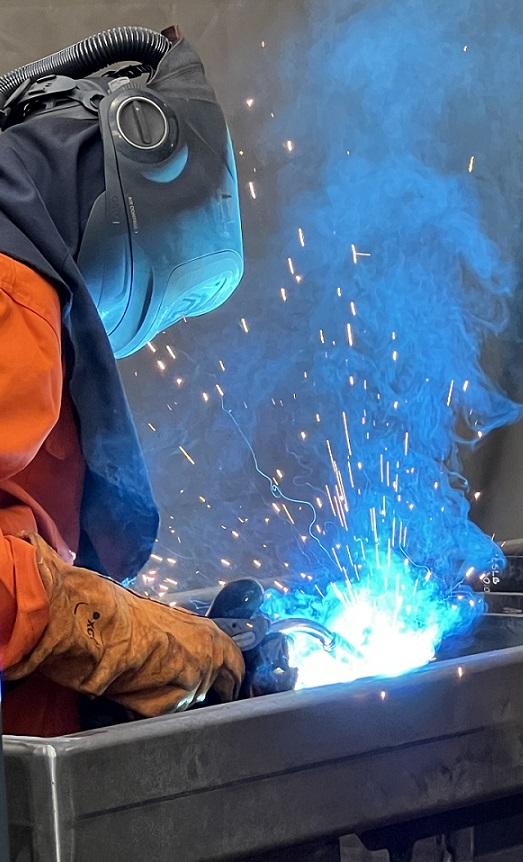 A factory worker welds a steel frame.