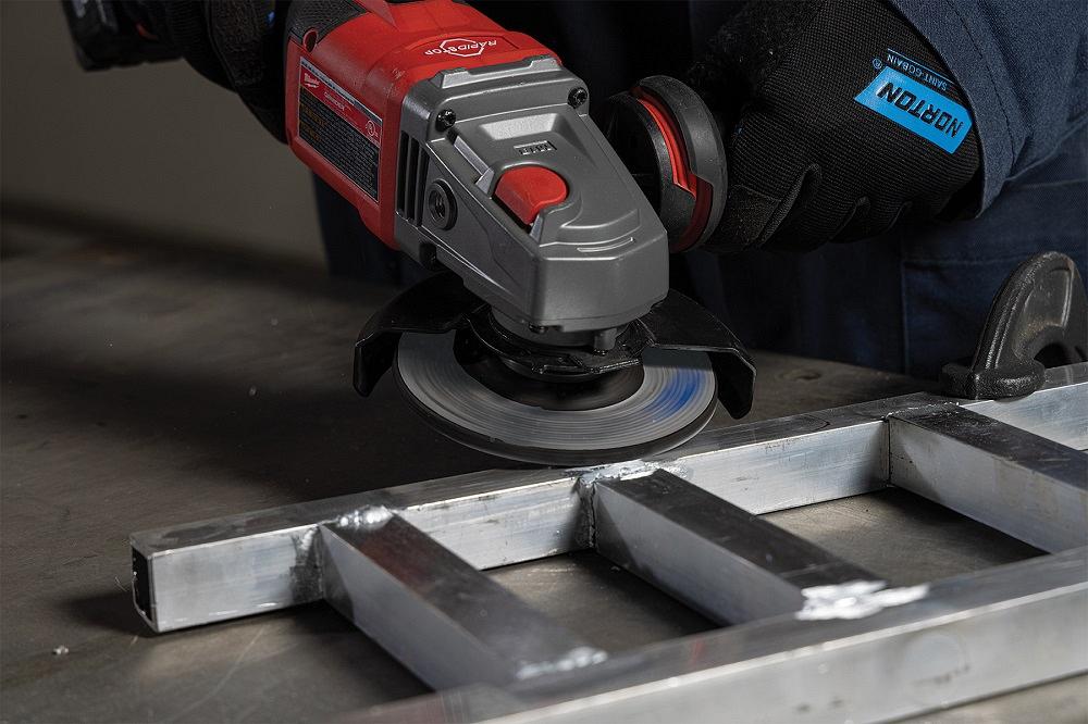 A fabricator uses a grinder on an aluminum workpiece.