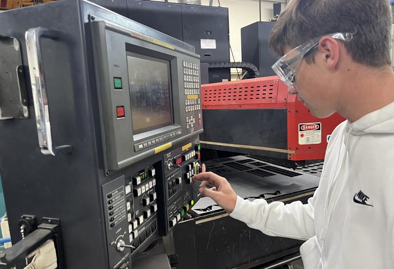 A student works on a machine's control panel.