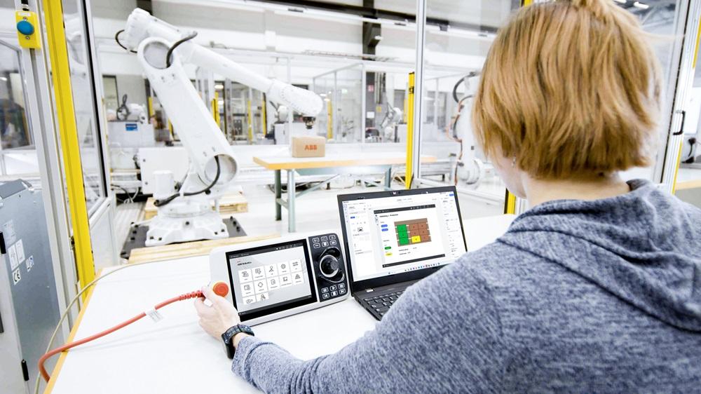 A person works on a computer that controls a robot.