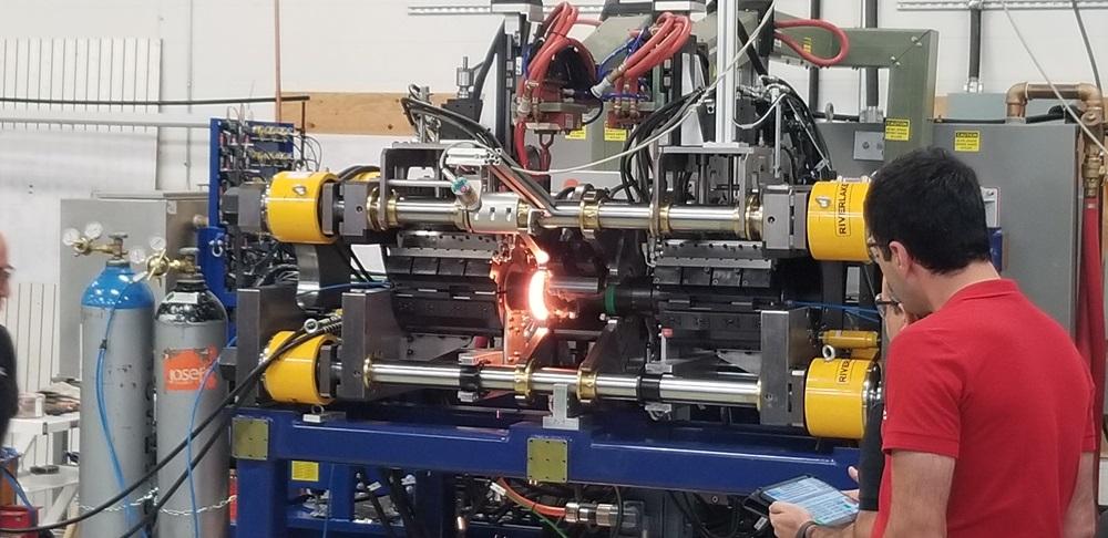 A machine operator watches induction-assisted friction welding take place.