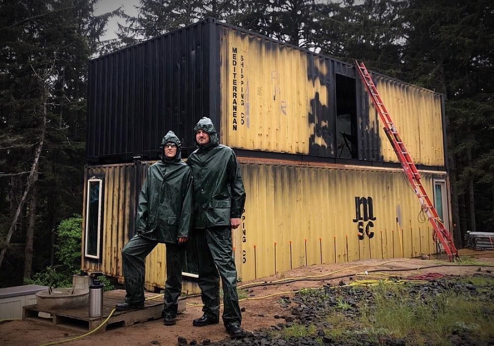Husband and wife standing in front of their steel shipping container home