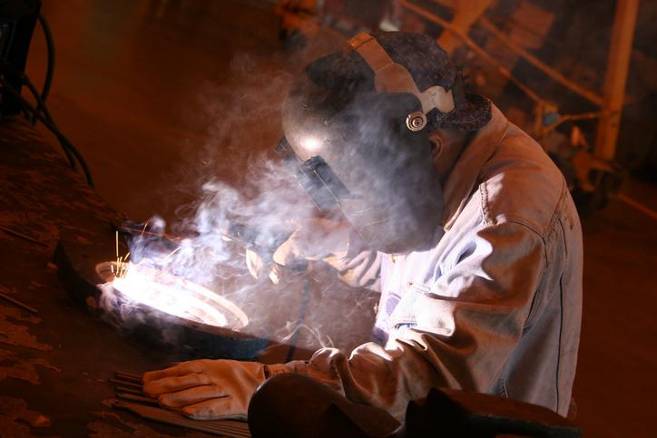 A welder works at his workbench. 