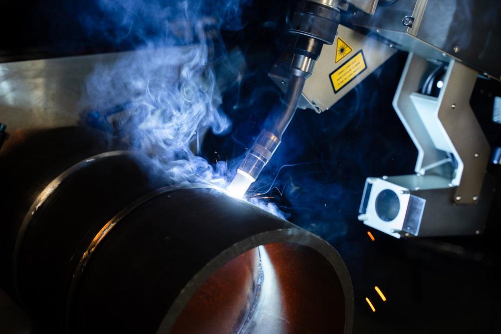 A robot welds a pipe.