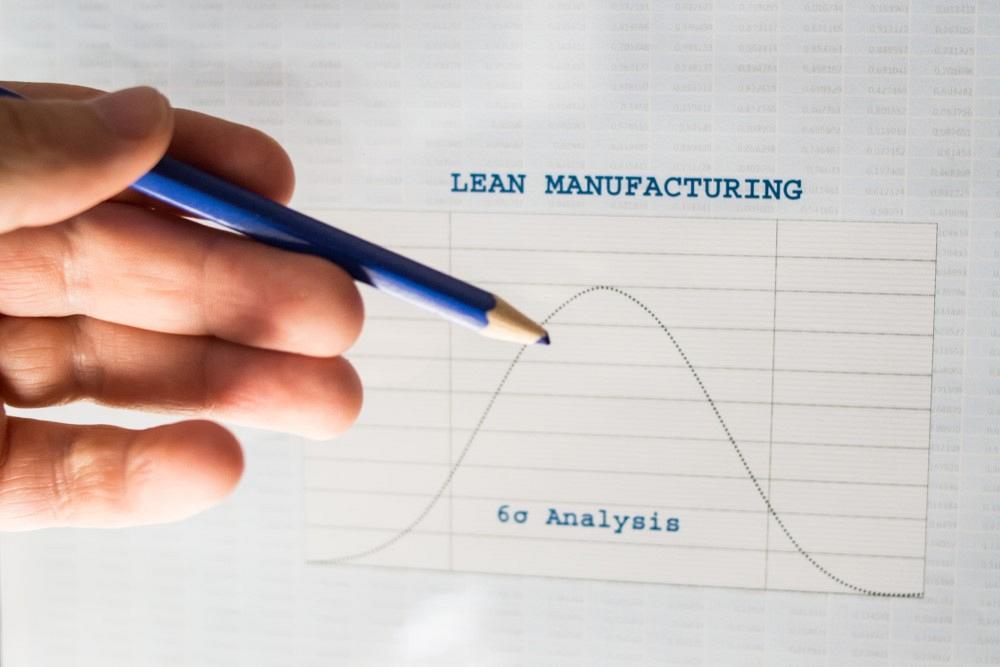 Male hand pointing with a blue pencil at a Lean manufacturing six sigma chart