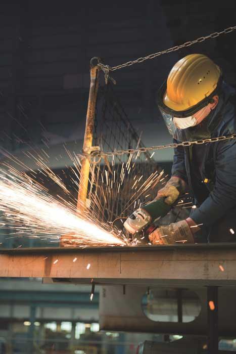 Angle grinder operator wearing safety glasses, clothing and helmet