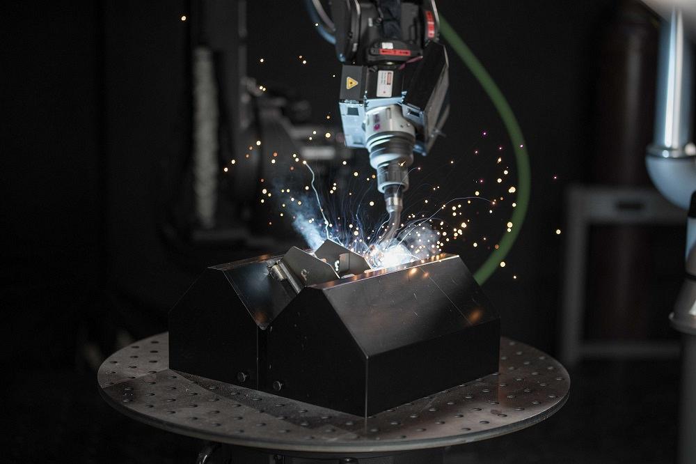 A robotic torch welds a metal part.