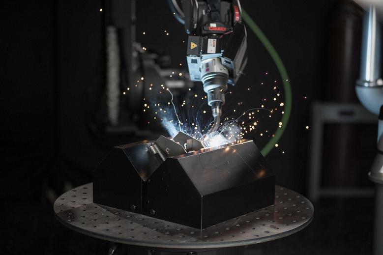 A robotic torch welds a metal part.