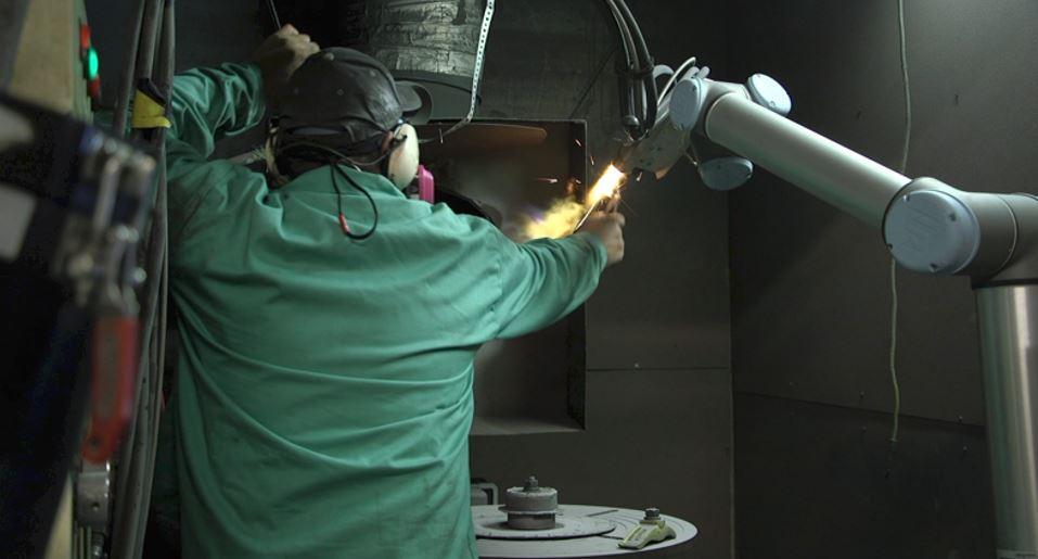 A worker guides a robot arm.