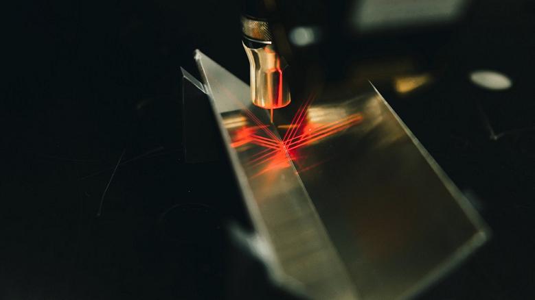 A metal seam is inspected with red laser light.