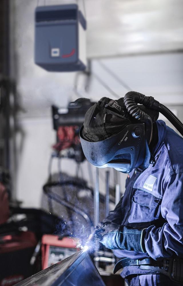 A person welds wearing PPE.