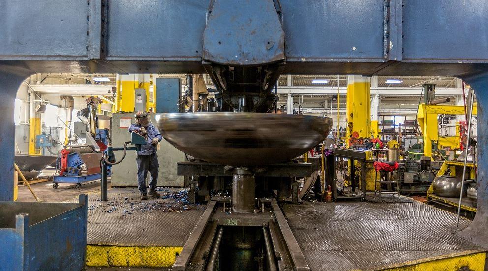 An operator watches as a tank head is formed.