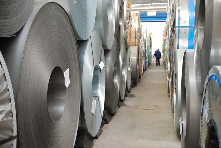 Rolls of sheet steel sit on a warehouse floor.