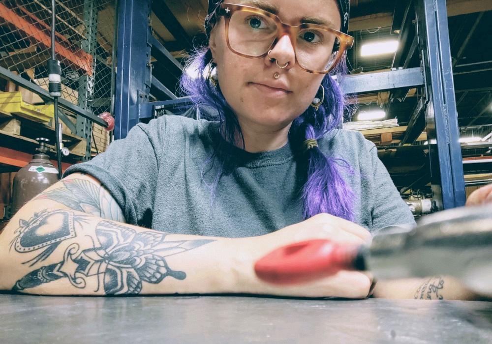 Female metal fabricator with tattoos