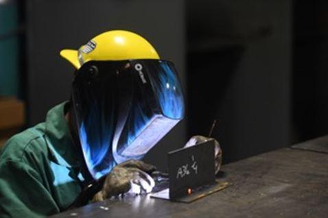 A young welder practices TIG welding.