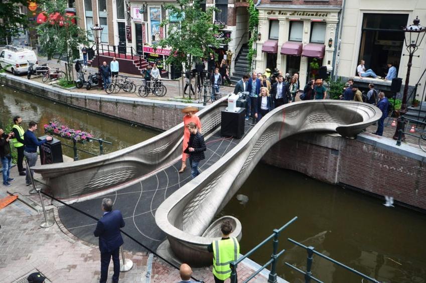 People walk across a pedestrian bridge over a small canal.