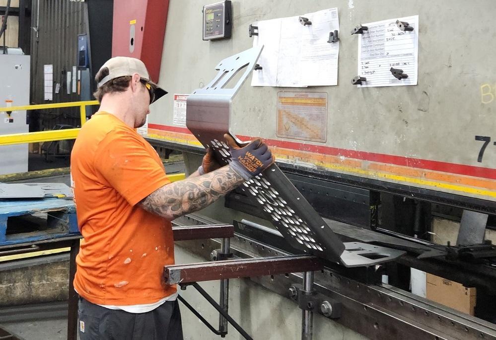 A man bends metal with a press rake