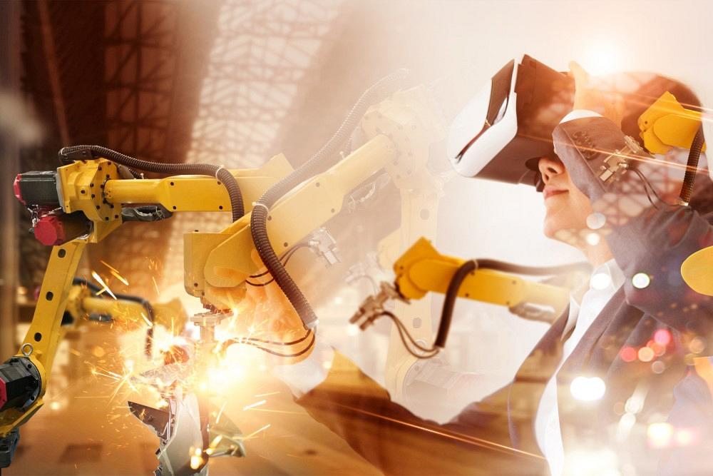 Engineer manager wearing virtual reality headset uses VR technology checking and controlling automation robot arms machine in intelligent factory industrial, Welding robotics and digital manufacturing. 