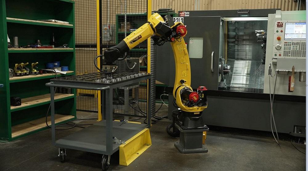 A robot loads metal blanks into a lathe.
