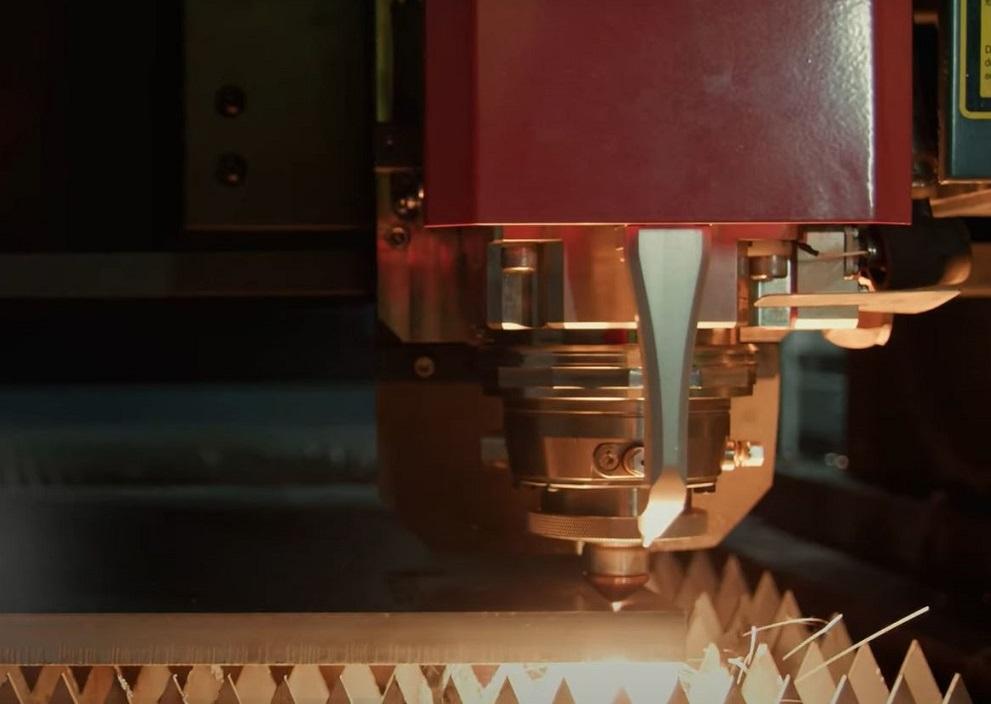 A laser cutting torch cuts a piece of sheet metal.