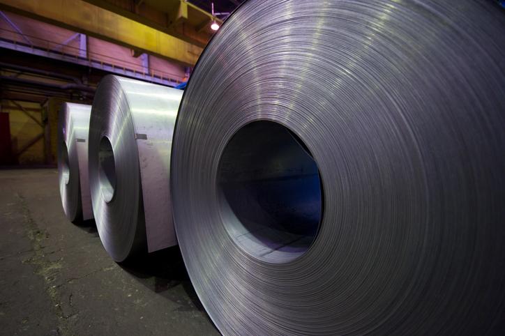 Three steel coils sit on a warehouse floor.