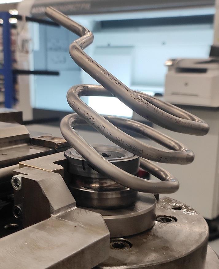 A coiled tube is formed on a bending machine.