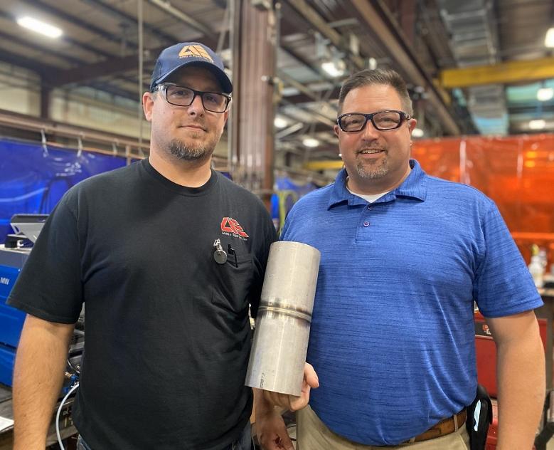 Two men show off a welded tube