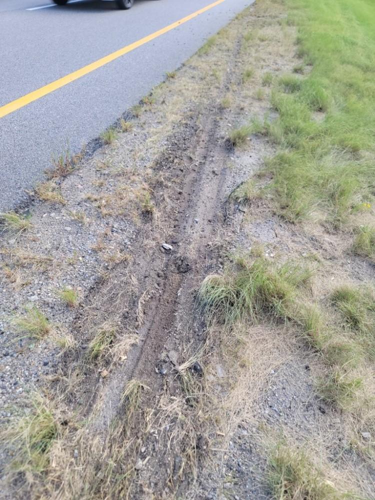 A long drag mark is seen in the dirt next to the highway.