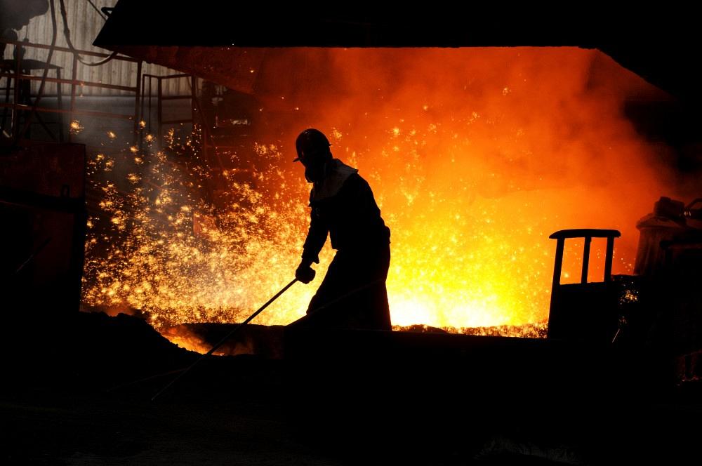 A worker cleans the area in front of a blast furnace.