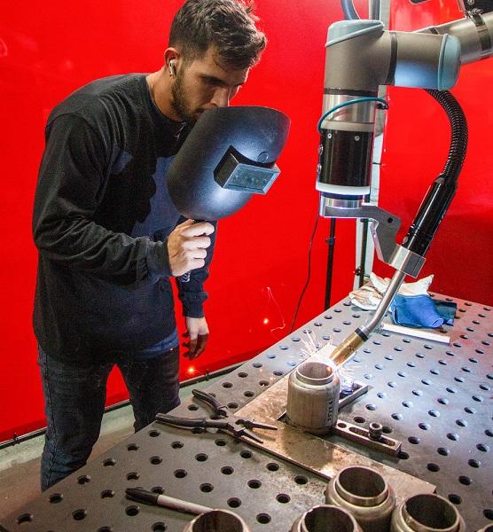 A man watches a robot welding.