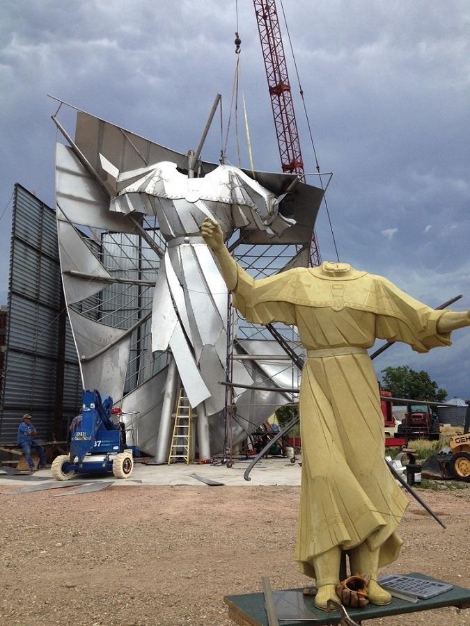 The stainless statue under construction stands behind a smaller replica.