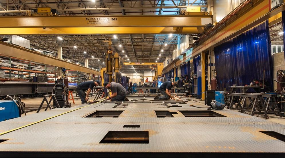 Metal fabricators work on a large workpiece.