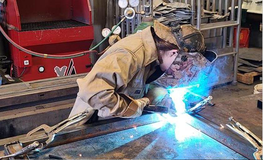 A welding student assembles frames to be used in the fabrication of cylinder racks.