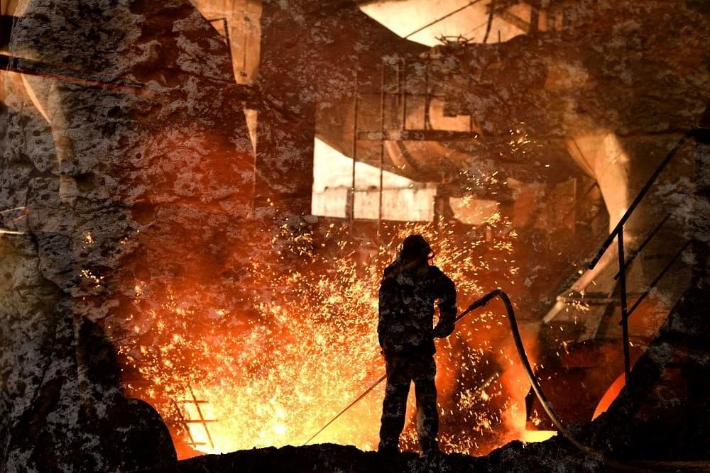 Man is working in the splashing molten iron at steel mill
